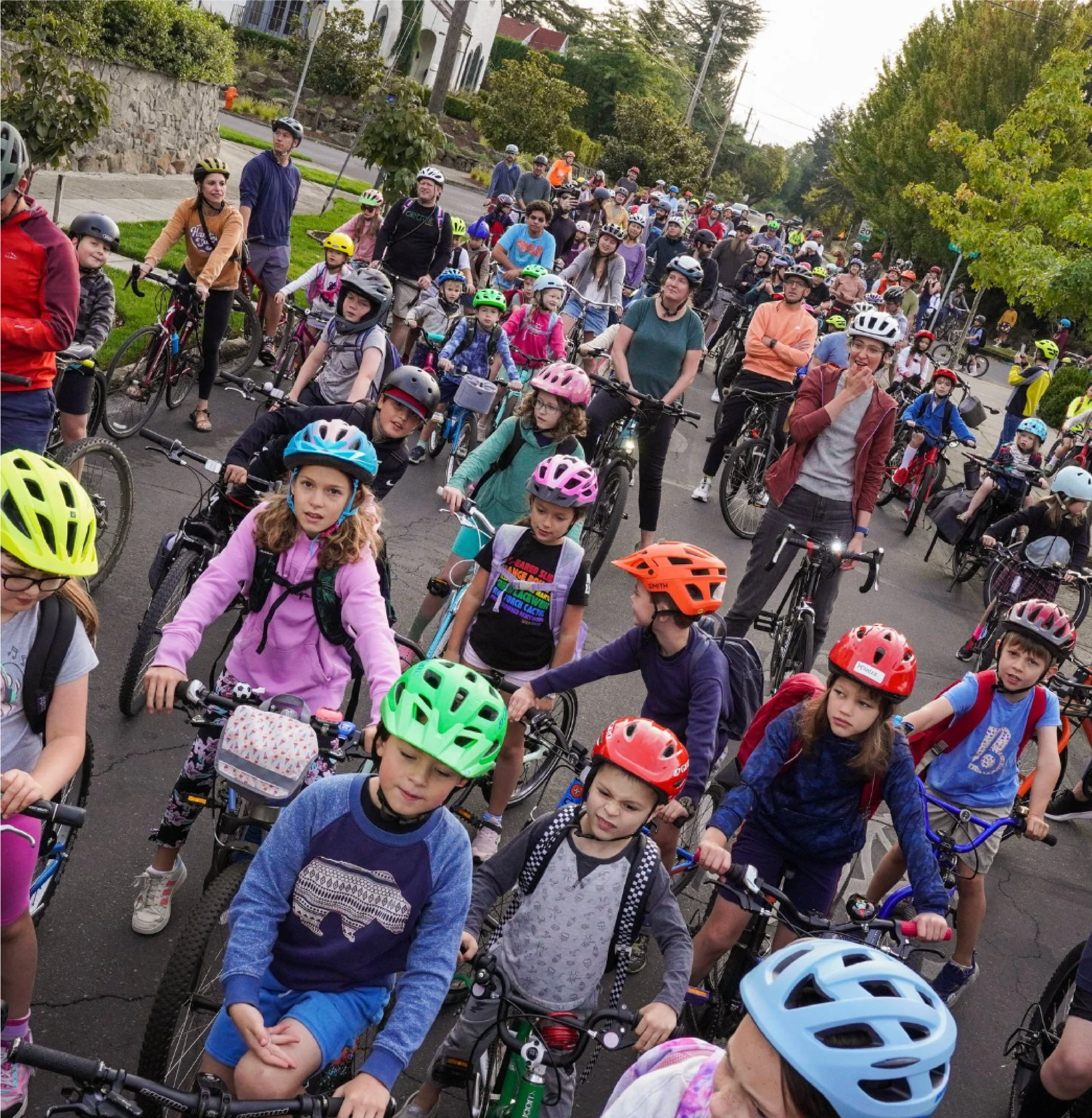 Large group of kids wearing helmets on bikes